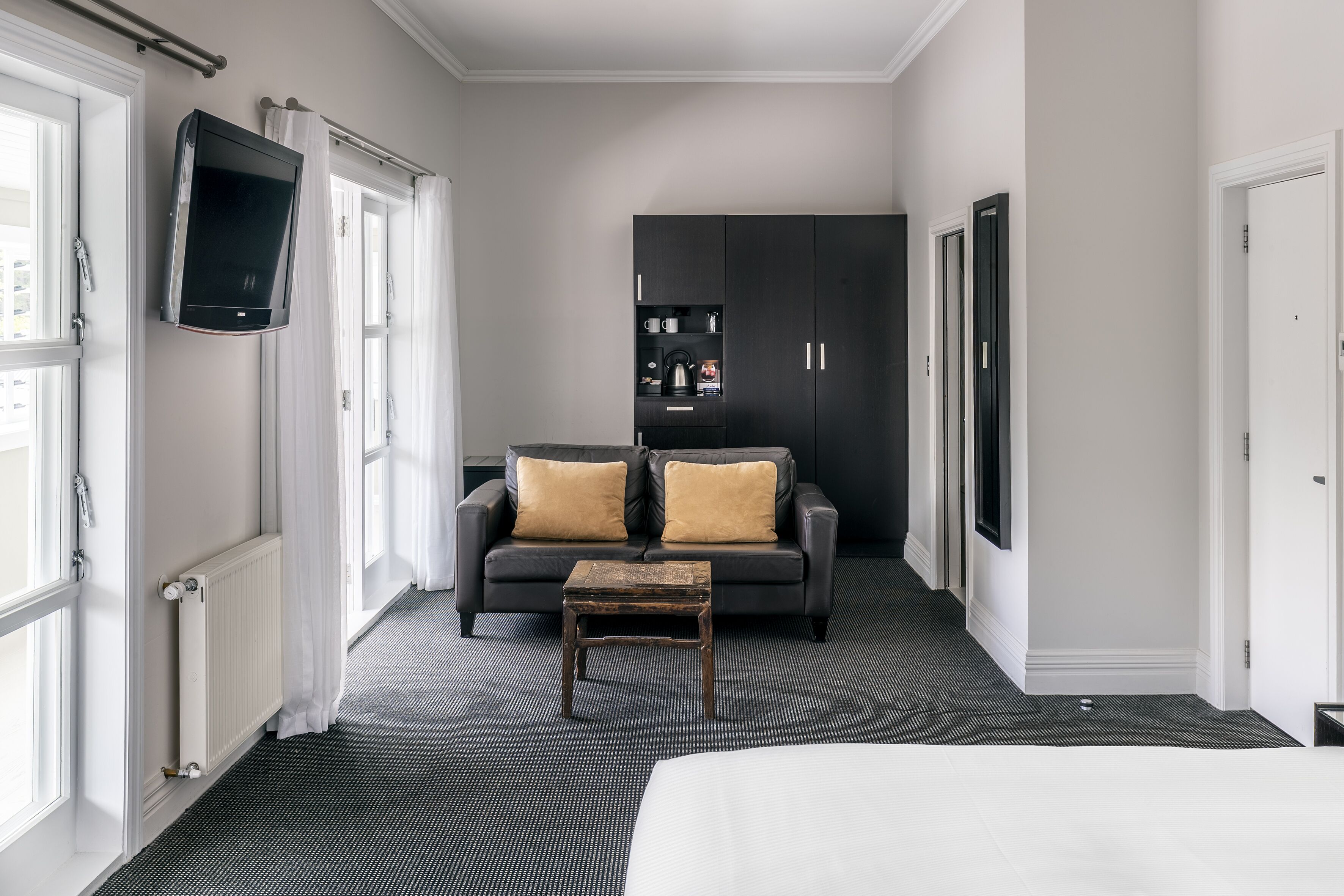A hotel room with a bed, a sofa, a coffee table, a TV, and a wardrobe.