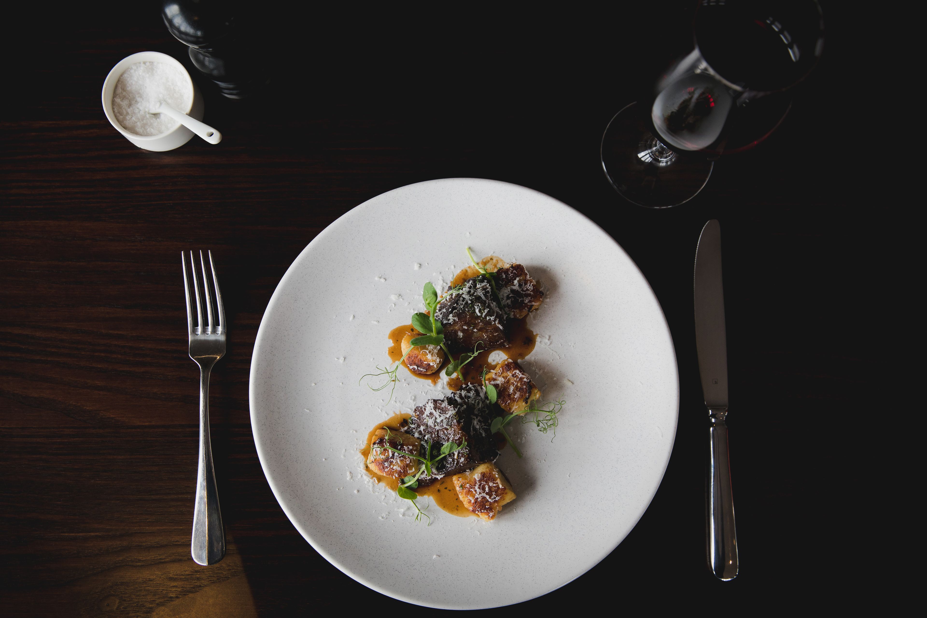 A plate of food with a fork and knife on a dark table.