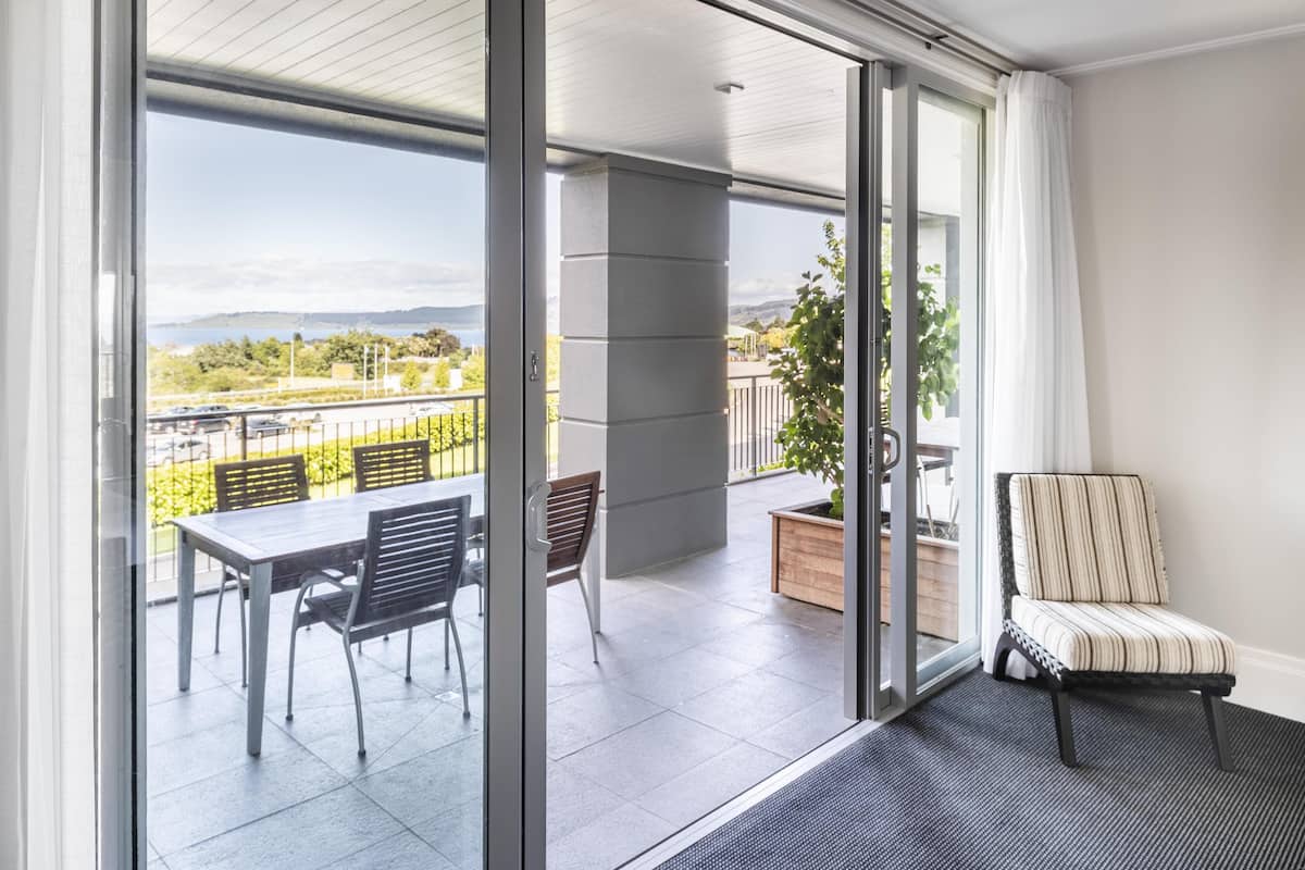 Un balcon avec une table et des chaises, un pot de fleurs et une chaise à rayures.