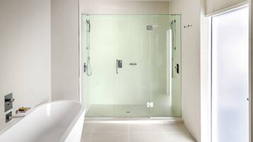 Un bagno moderno con cabina doccia in vetro, una vasca da bagno freestanding e una porta bianca semplice.