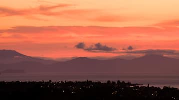 A coastal sunset view with distant mountains and a town in the foreground.
