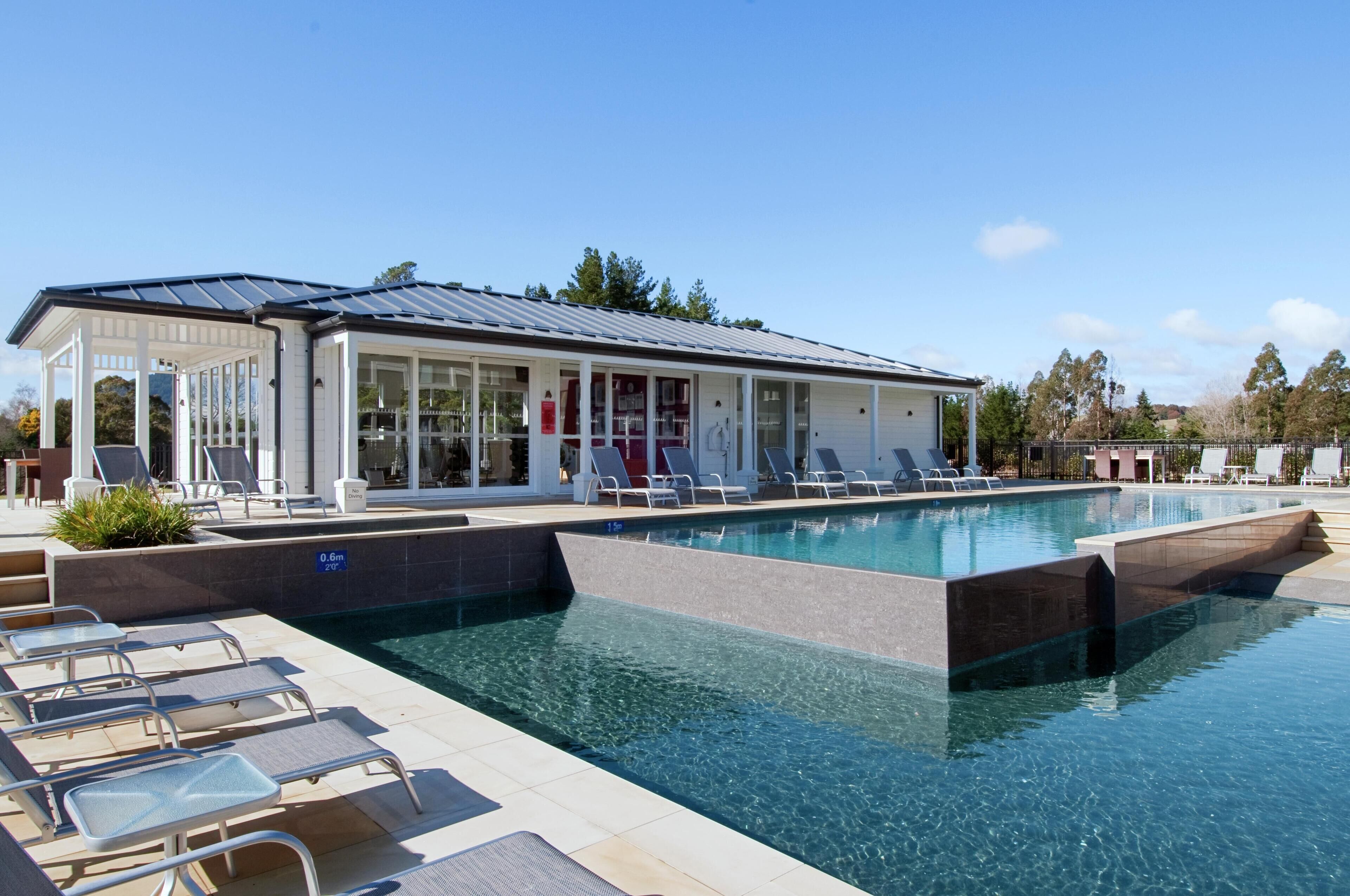 A pool area with lounge chairs and a covered structure.