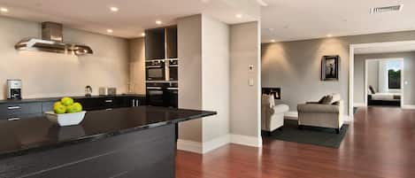 A modern kitchen with a black countertop and a bowl of fruit.