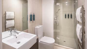 A modern bathroom with a glass-enclosed shower, a white sink, and a toilet.