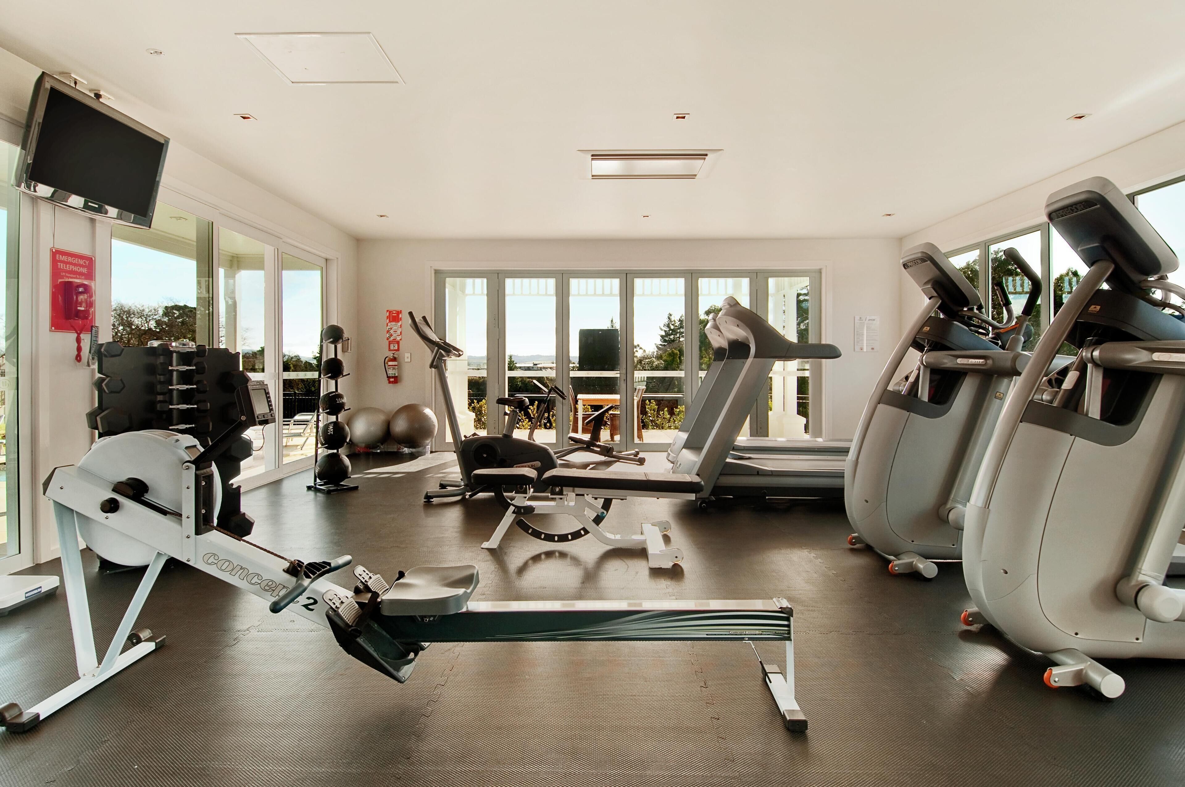 Un gimnasio con máquinas de cardio, equipo de pesas y una máquina de remo.
