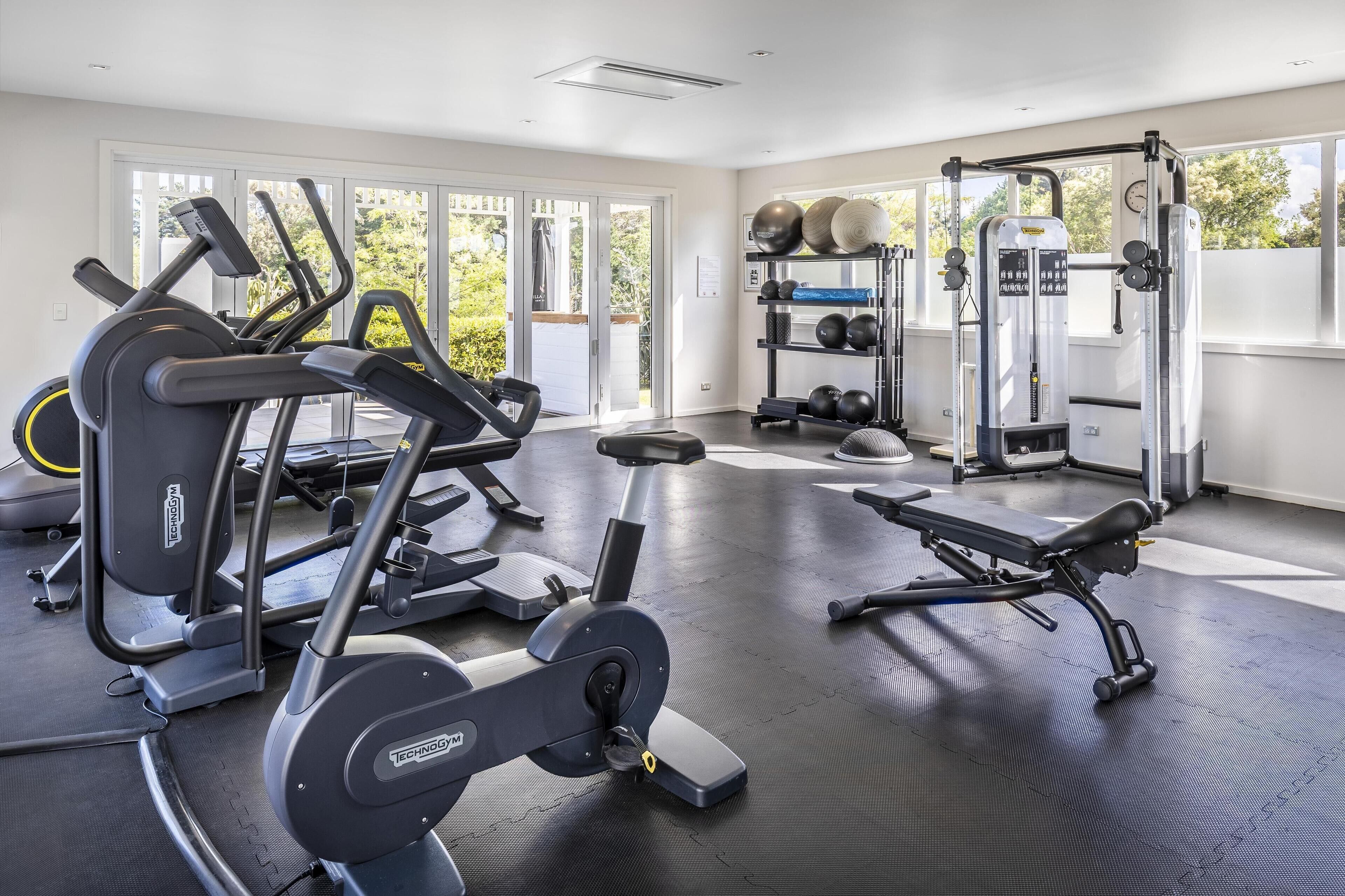 Une salle de sport équipée de machines de cardio, de matériel de musculation et d’un banc.