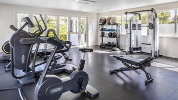 Une salle de sport équipée de machines de cardio, de matériel de musculation et d’un banc.