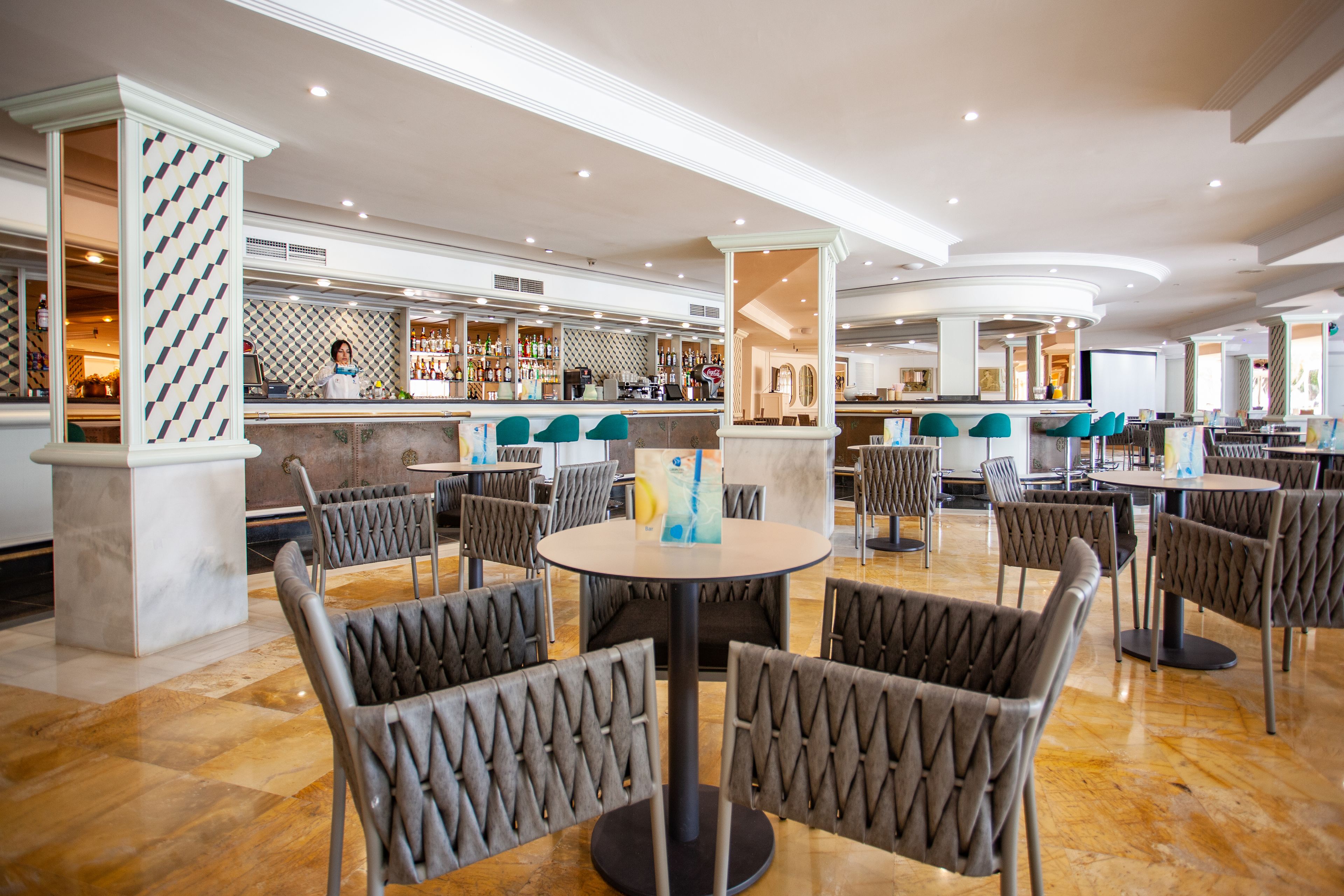 Eine geräumige Hotelhalle mit mehreren Sitzbereichen, einer Bar und einer gut beleuchteten Decke.