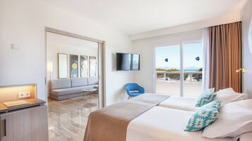 Habitación de hotel con cama, escritorio, televisión, sofá y vistas al exterior.
