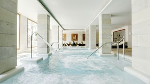 Un área de spa con un jacuzzi, una zona de estar y una escalera que lleva a otro nivel.