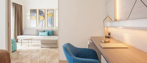 Un salon moderne avec un canapé, un fauteuil bleu, une table basse et des œuvres d’art accrochées au mur.