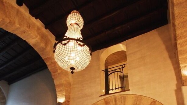 A spacious lobby with high ceilings, arched doorways, and a large chandelier.