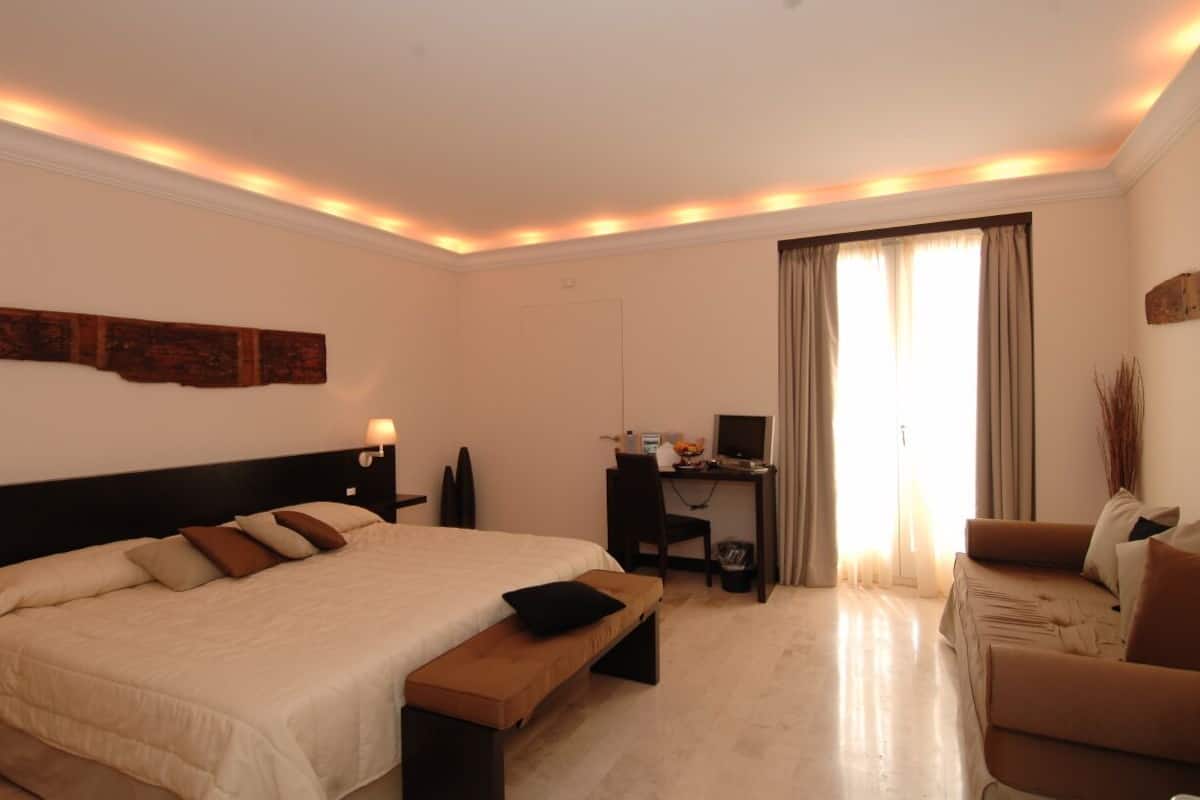 Una habitación de hotel con una cama grande, un escritorio con computadora, una silla y un sofá.