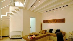 A modern living room with a built-in sofa, a dining table, and a staircase.