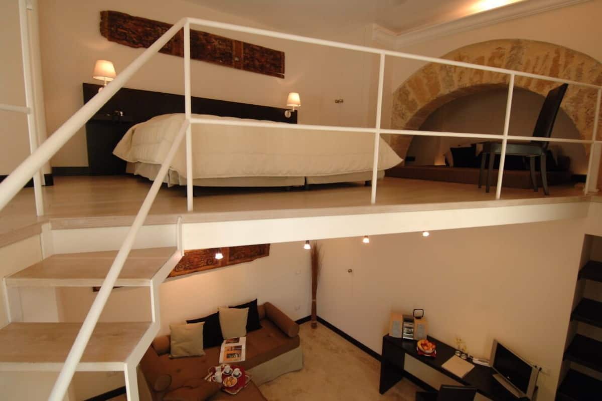 Un dormitorio con varios niveles y zona de altillo, una escalera, un sofá y un comedor.