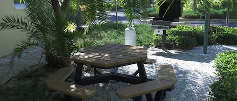 A picnic table with benches, surrounded by gravel and greenery.