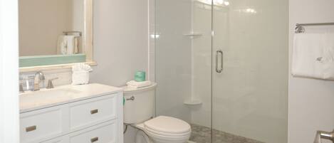 A bathroom with a glass-enclosed shower, a white sink, and a toilet.