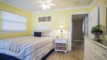 A bedroom with a bed, nightstand, lamp, and a ceiling fan.