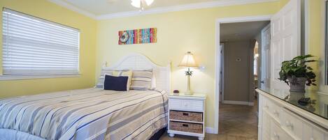 A bedroom with a bed, nightstand, lamp, and a ceiling fan.