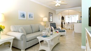 A living room with a striped sofa, a coffee table, and a dining area with chairs and a table.