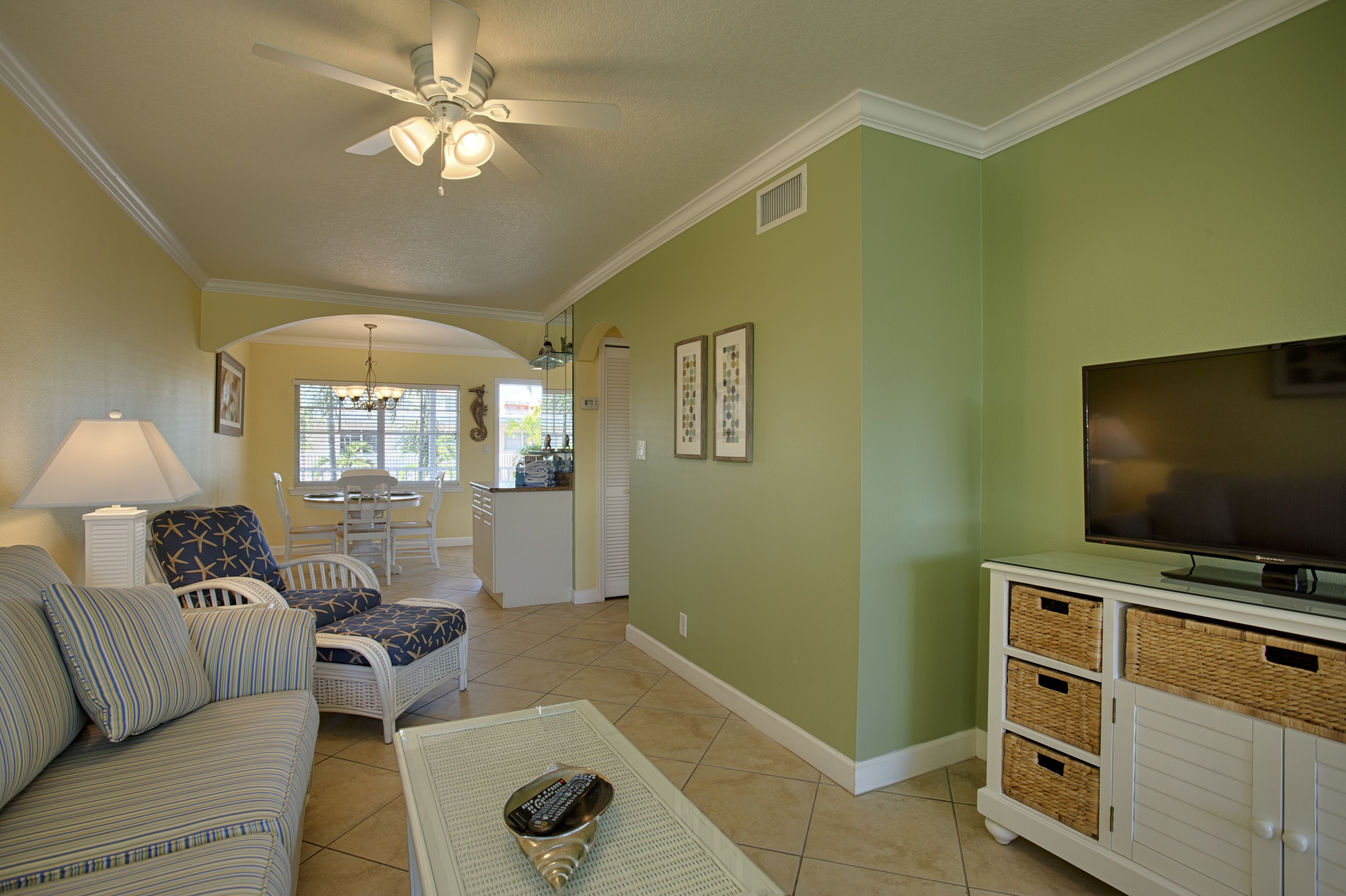 A living room with a sofa, chairs, a coffee table, a TV, and a ceiling fan.