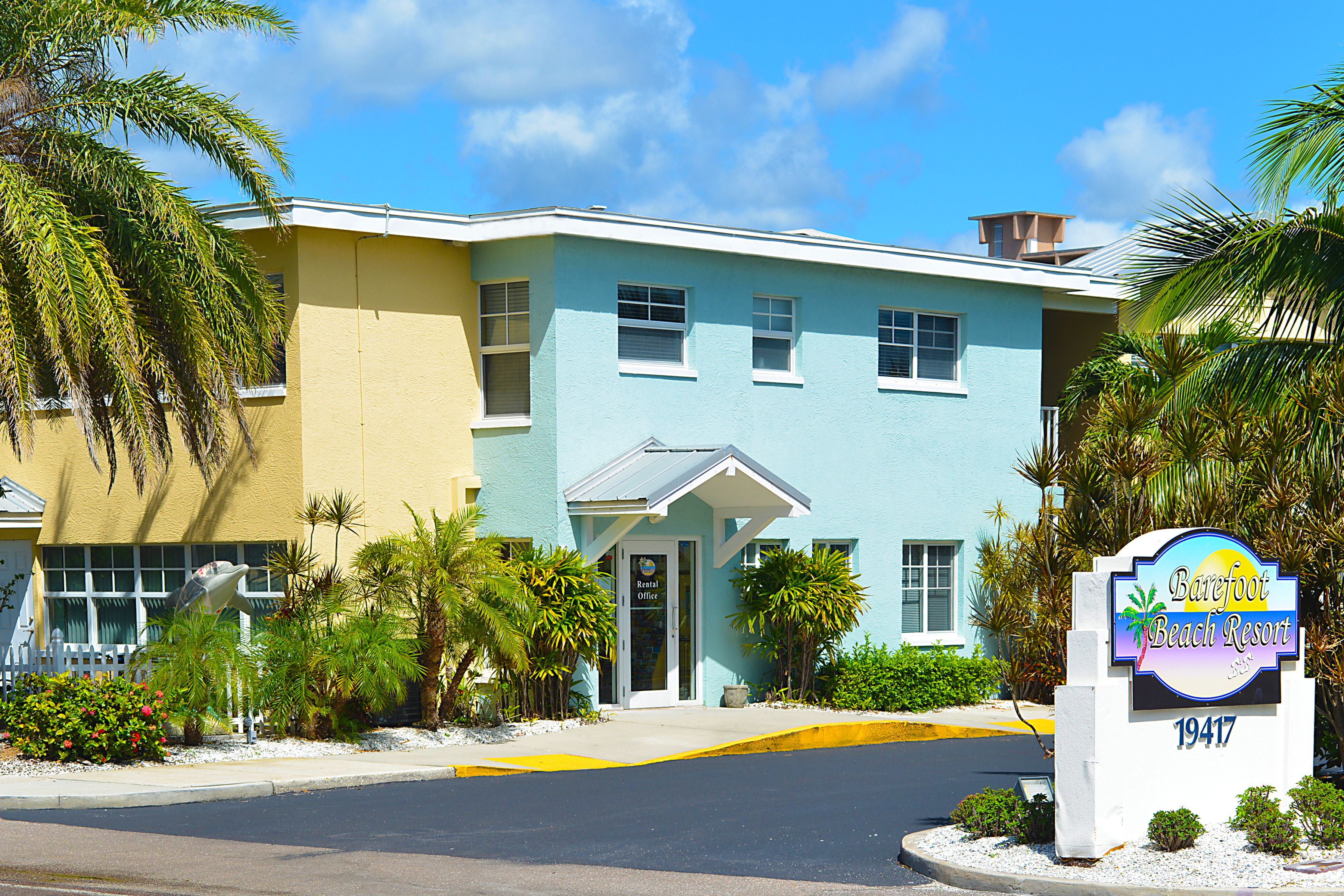 A two-story building with a sign for Barefoot Beach Resort.