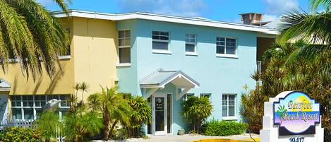 A two-story building with a sign for Barefoot Beach Resort.