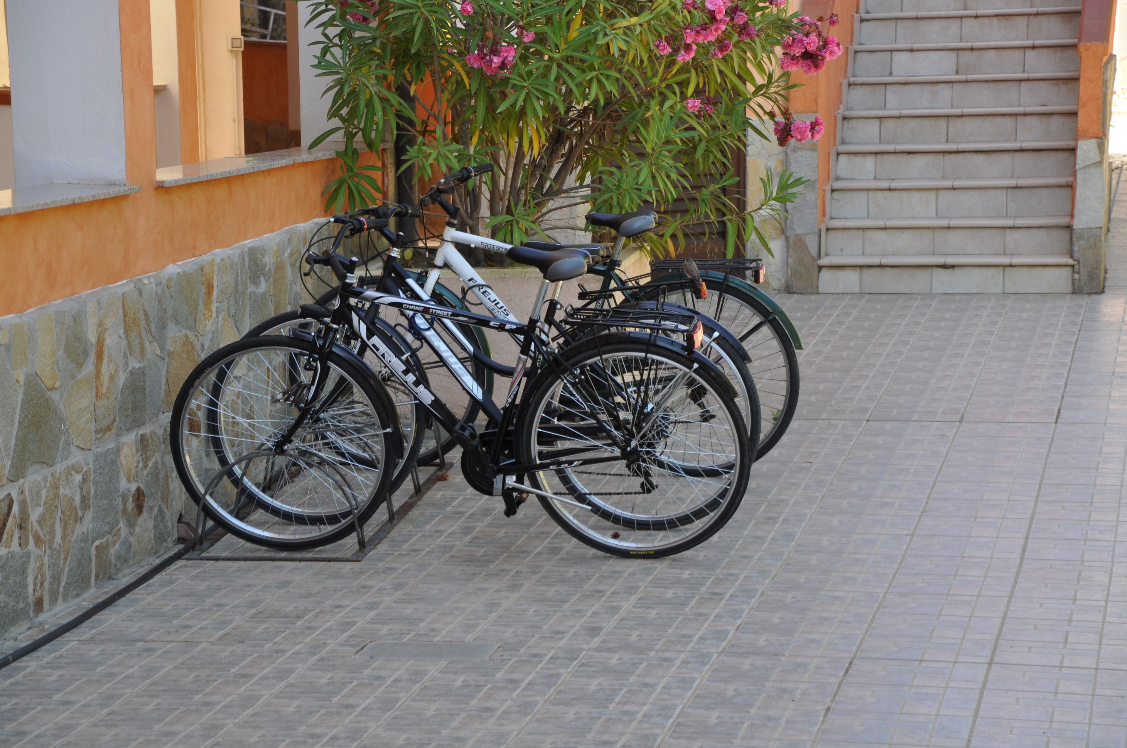 A bicycle rack with several bicycles parked against a stone wall.