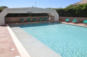 Una piscina al aire libre de temporada, sombrillas