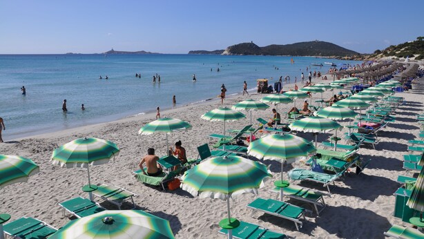 A beach with rows of green and white striped umbrellas and lounge chairs. - Palm Village (Villasimius)