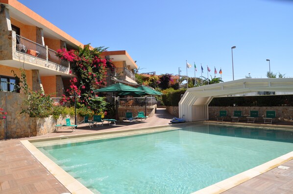 Una piscina al aire libre de temporada, sombrillas