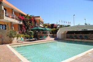 Una piscina al aire libre de temporada, sombrillas, tumbonas
