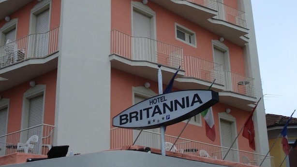 Ein mehrstöckiges Hotel namens "HOTEL BRITANNIA" mit Balkonen, einem Schild und Flaggen.