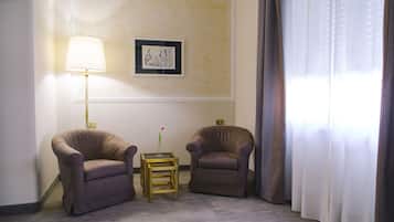 Una habitación con dos sillones, una mesita con un florero, una lámpara y un cuadro en la pared.
