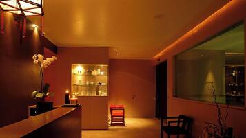 Un interno moderno con una reception, una teca in vetro, una poltrona rossa e un'ampia finestra.