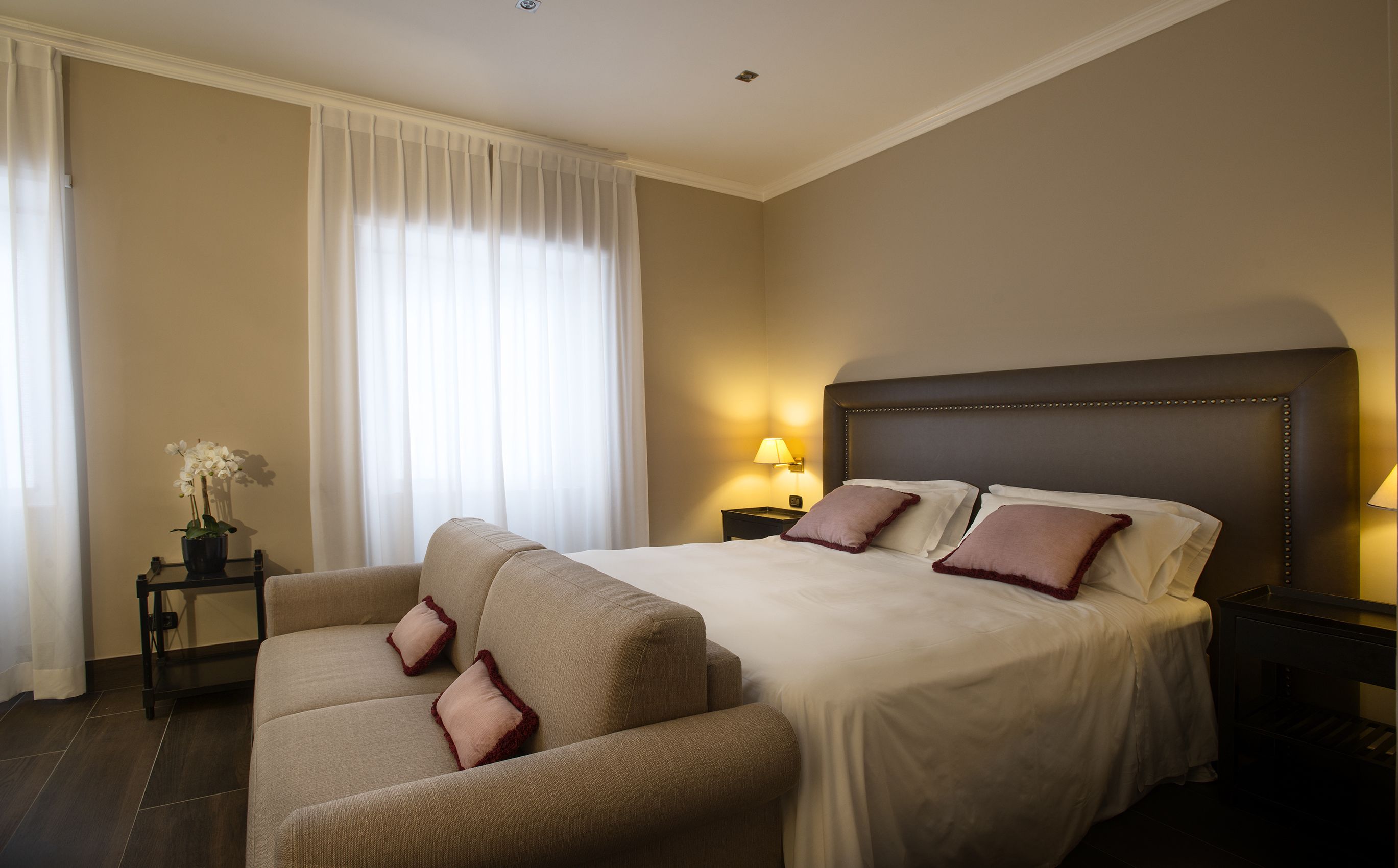 Una habitación de hotel con cama, sofá, mesita de noche y lámpara.
