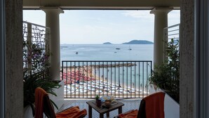 A balcony with a view of the sea, a table with a bowl and a bottle, and chairs with orange towels. - Hotel Venere Azzurra (Lerici)