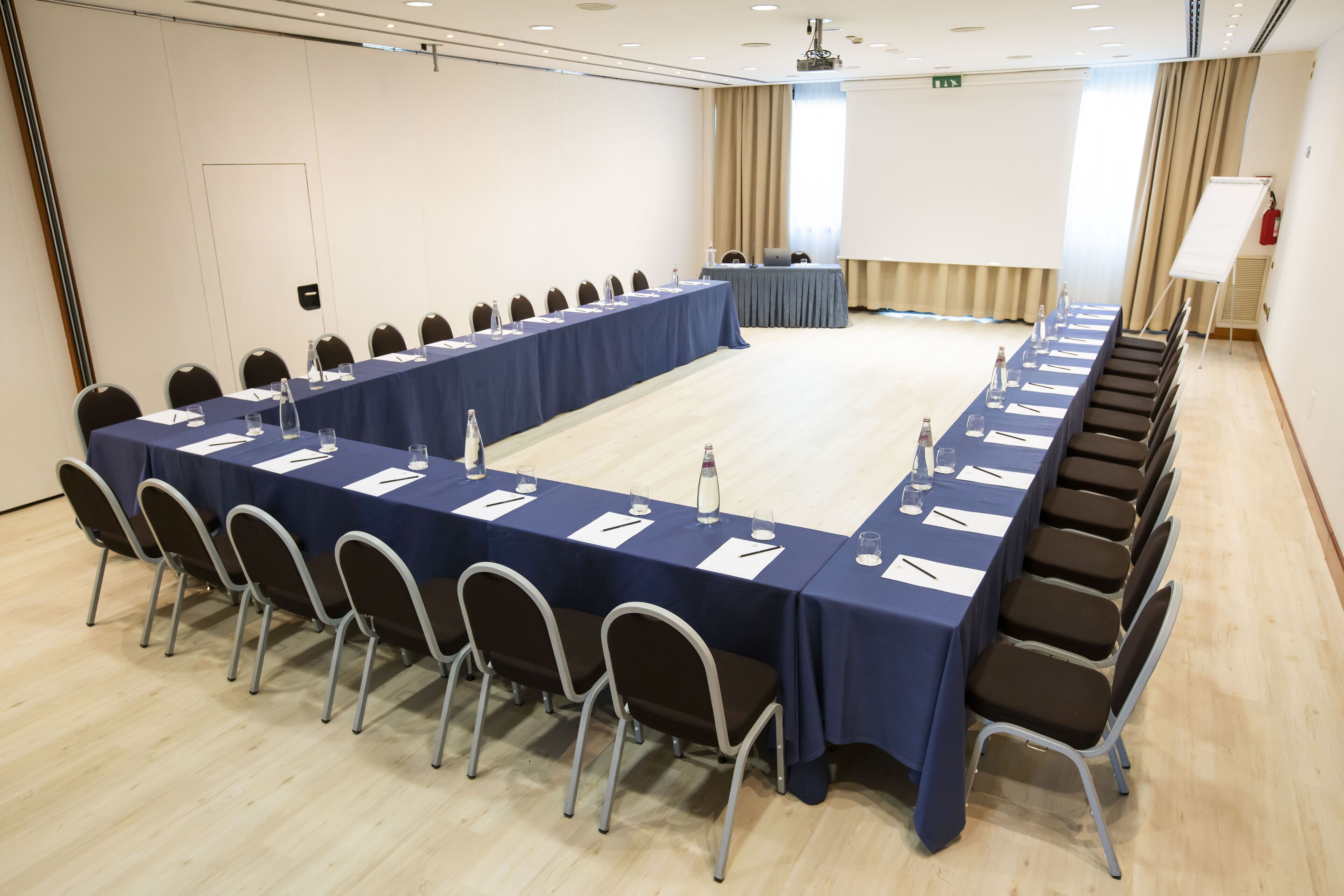 Uma sala de conferências com uma mesa grande, cadeiras e um quadro branco.