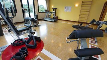 A gym with various exercise equipment, a red mat, and a wall calendar.