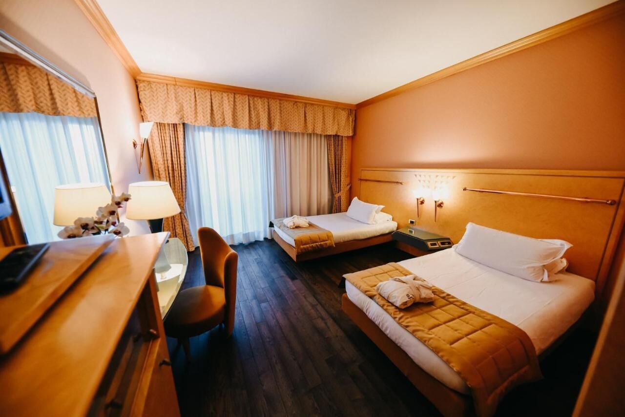 Habitación de hotel con dos camas, un escritorio y una silla.