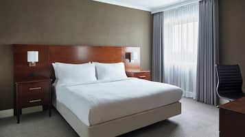 A hotel room with a large bed, two bedside tables, a desk, and a chair.