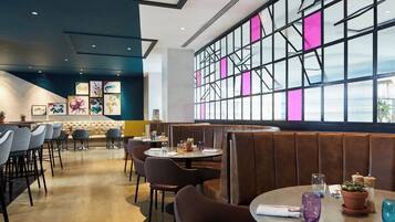 A restaurant with booth seating, tables, and a large window with pink accents.
