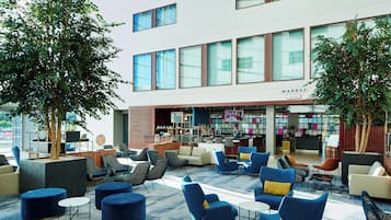 A modern lounge area with seating, a bar, and a view of the building's exterior.