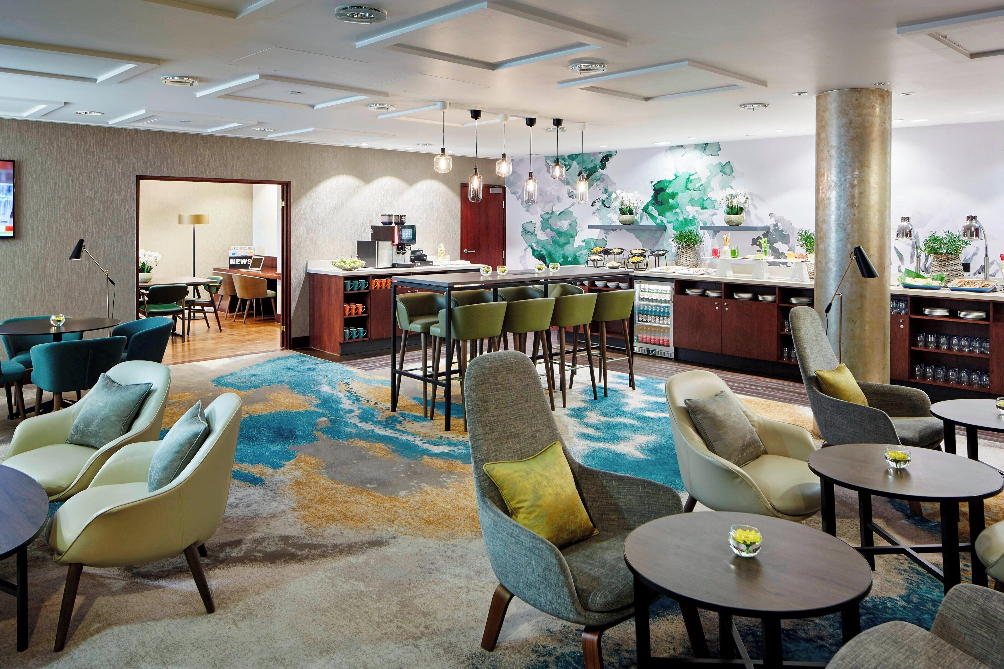 Un moderno vestíbulo de hotel con zona de bar, asientos y una pared decorativa.