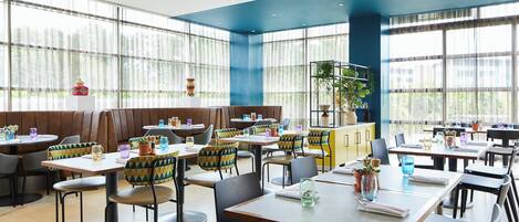 A modern restaurant with high ceilings, large windows, and a variety of seating options including booths and tables.