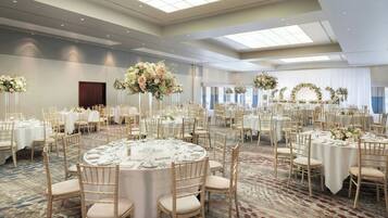 A large banquet hall with round tables, white tablecloths, and gold chairs.