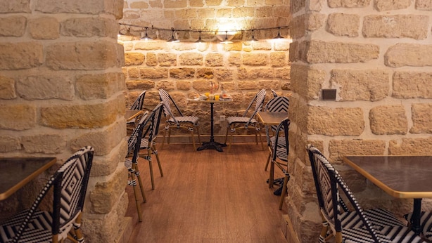 An interior with stone walls, wooden flooring, and patterned chairs around tables. - Ibis Styles Paris Batignolles (Paris)