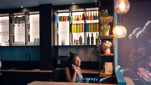 A bar area with shelves of beverages, a counter, and a decorative wall. - Ibis Styles Paris Batignolles (Paris)