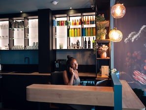 Angolo bar con scaffali pieni di bevande, un bancone e una parete decorativa.
