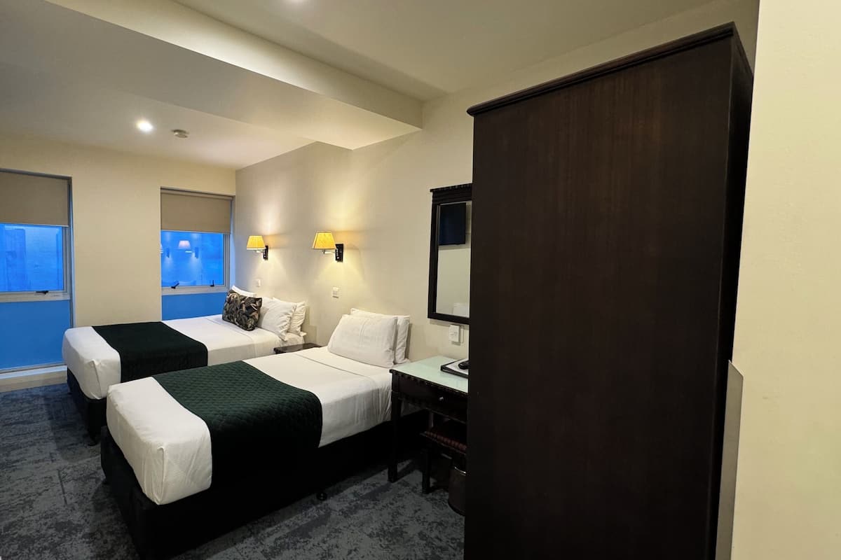 Ein Hotelzimmer mit zwei Betten, einem Schreibtisch, einem Stuhl, einem Spiegel und einem Fenster mit Blick.